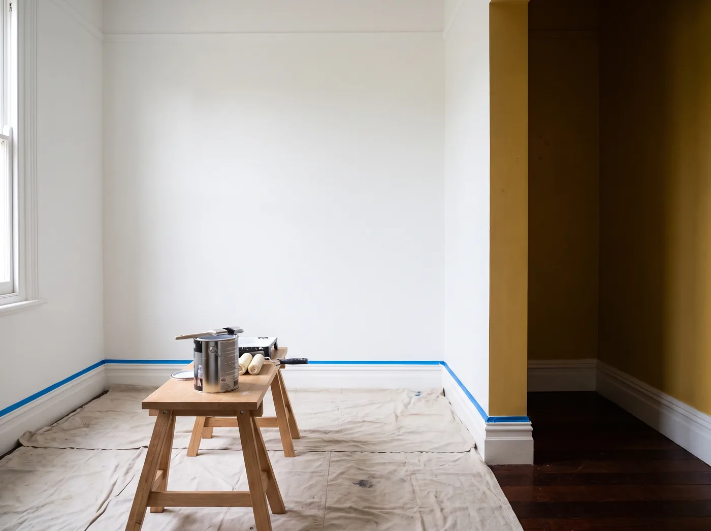A room part way through a repaint, drop sheets down and the first coat on